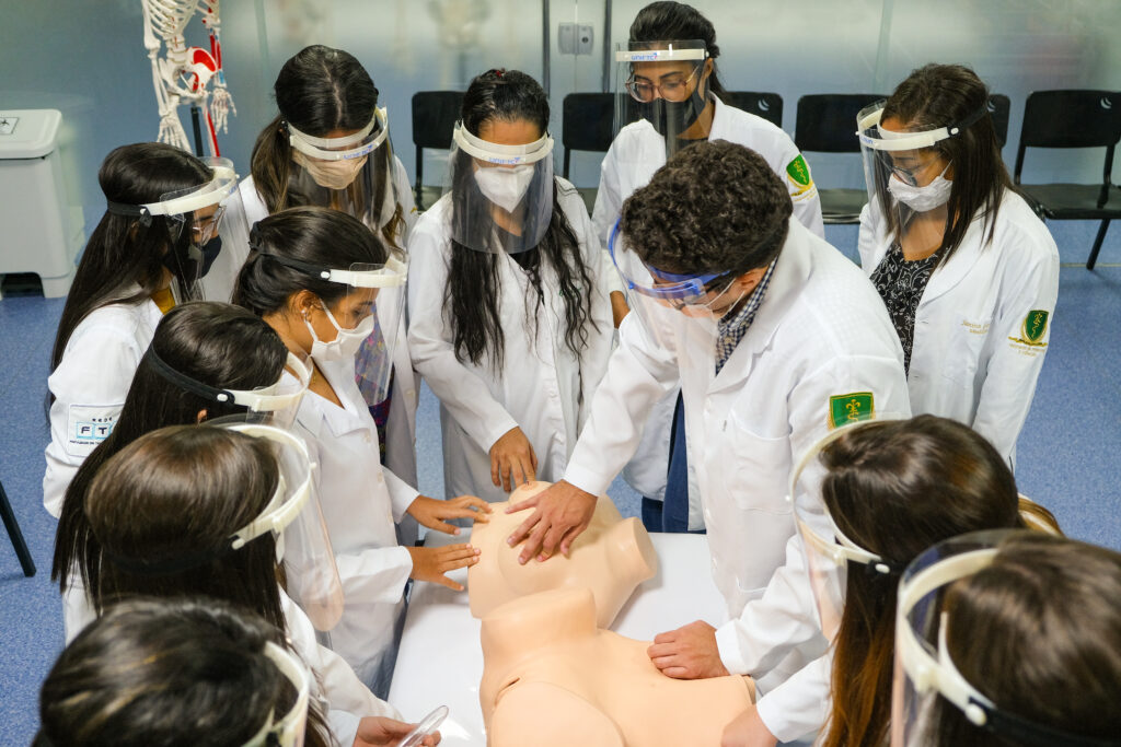 Professor da graduação da Medicina FTC dando aula com protótipos mamários e ginecológicos